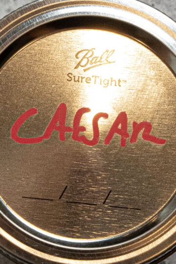 A gold Ball SureTight jar lid with CAESAR written in red marker across the top, and two blank lines underneath.