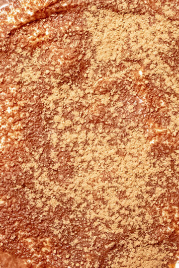 A close-up of a creamy dessert topped with a generous dusting of cocoa powder, creating a textured, chocolatey surface.