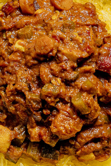 A close-up of a hearty, chunky vegetable and meat stew served over a bed of spaghetti squash strands.