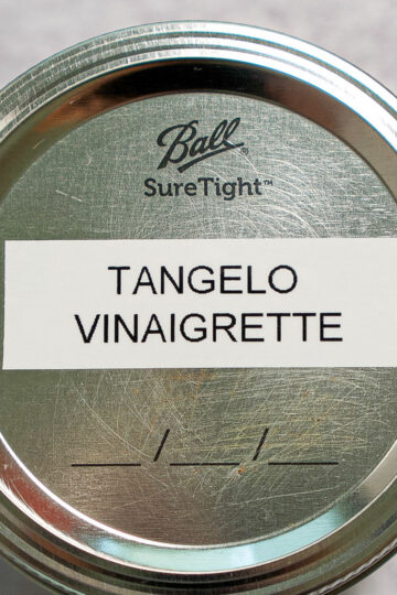 A metal jar lid labeled TANGELO VINAIGRETTE with the Ball SureTight logo above the label and a blank name/date section below.
