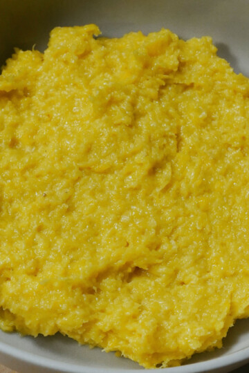 A close-up of a bowl filled with smooth, yellow mashed food, resembling mashed plantains or a similar starchy dish.