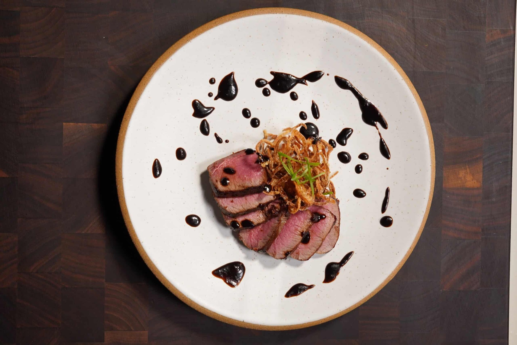 Sliced venison topped with shallots fried until light amber and crisp.
