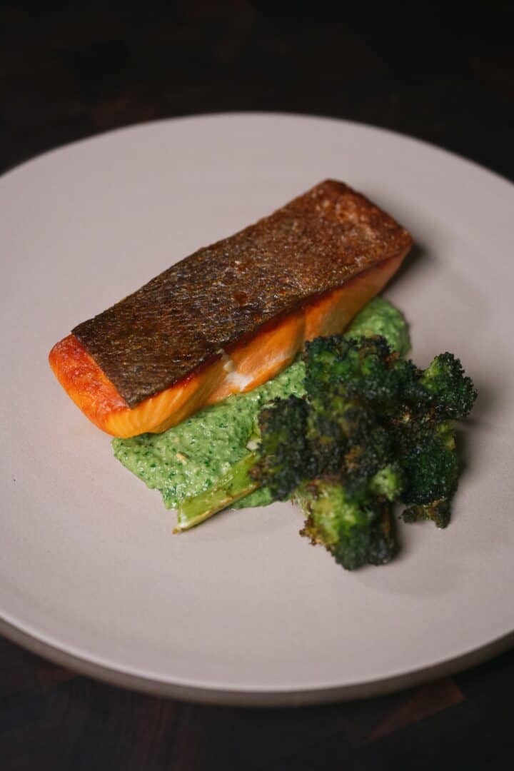 Crispy skin Ora King salmon resting on snap pea pesto with roasted broccoli alongside